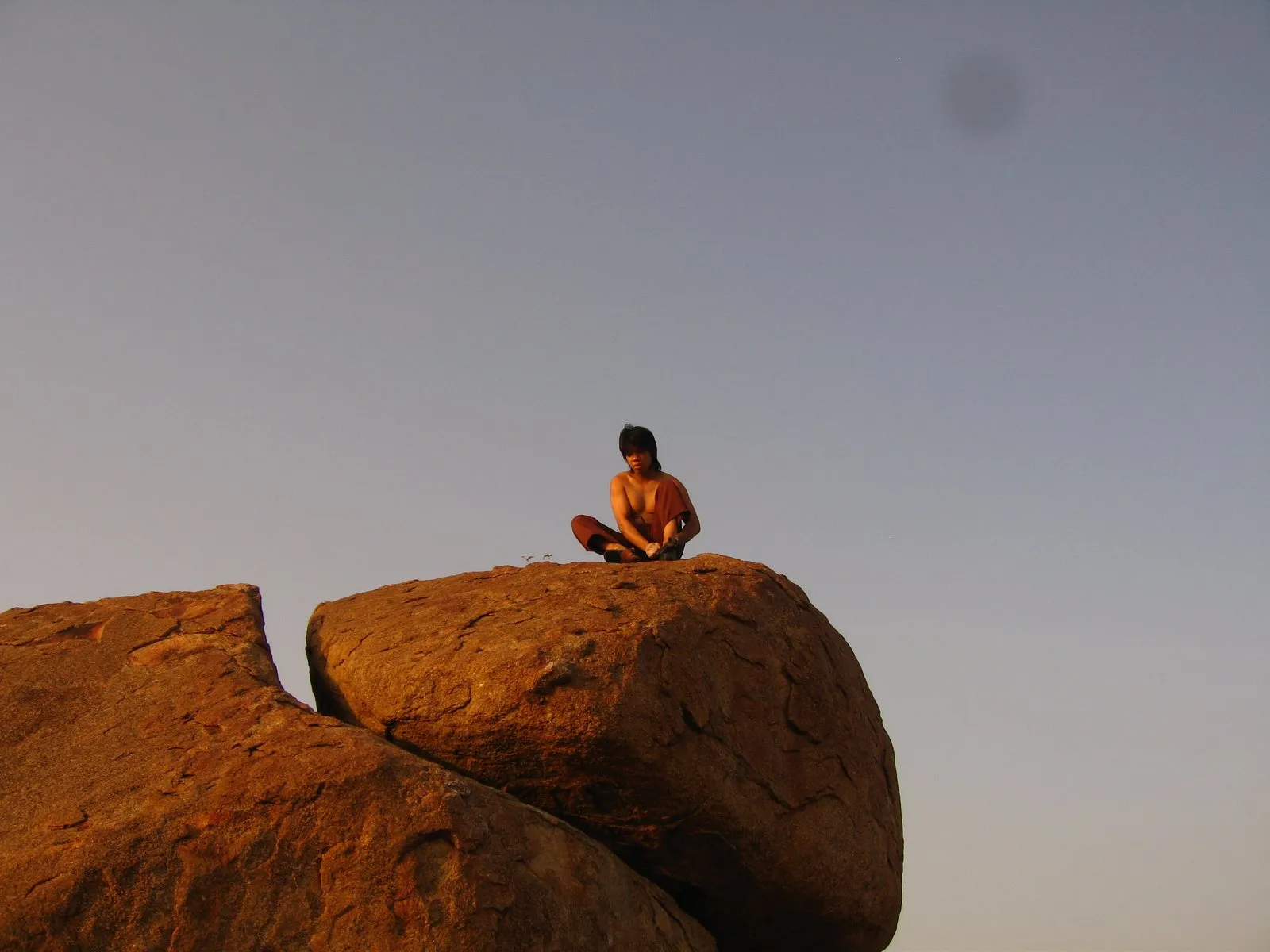 Sitting on top of a granite boulder at sunset in Hampi, India.