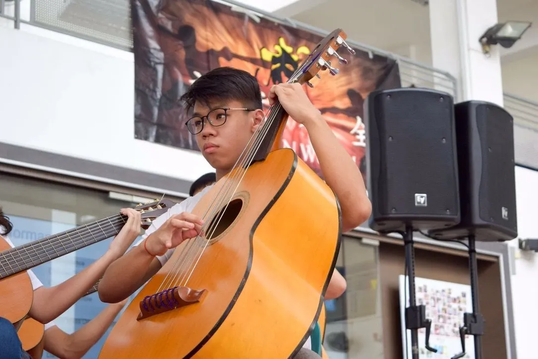 Playing a guitarron, a large fretless bass guitar, at an outdoor performance.