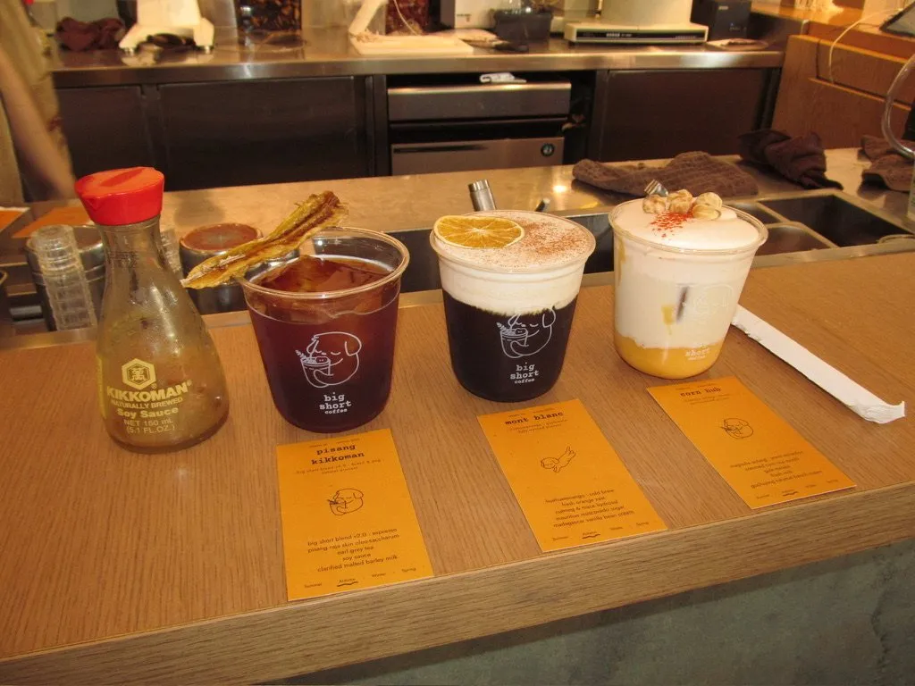Three specialty coffee drinks on a counter beside their tasting notes.