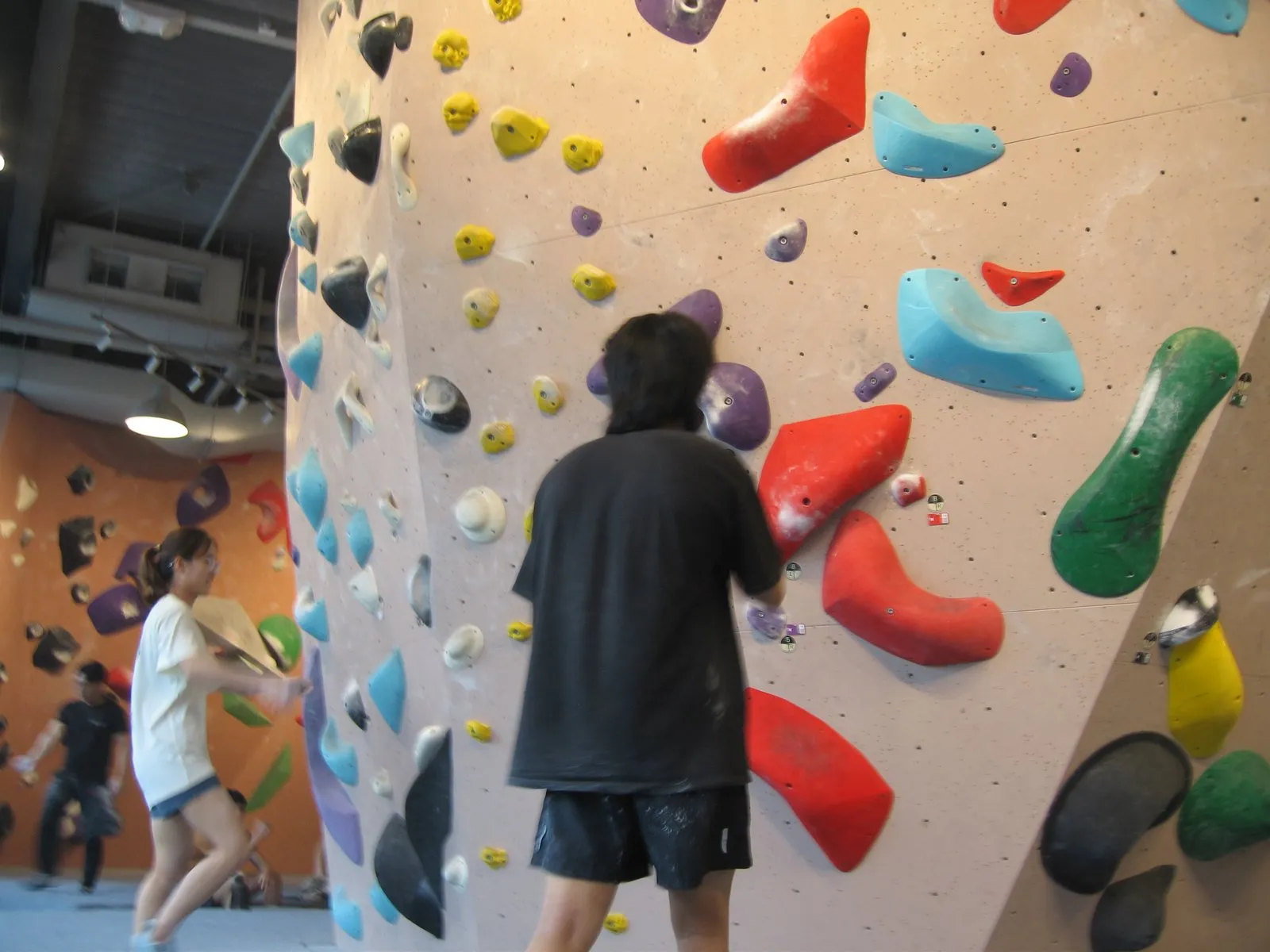 A bouldering gym, mid-session, with a wall of coloured holds.