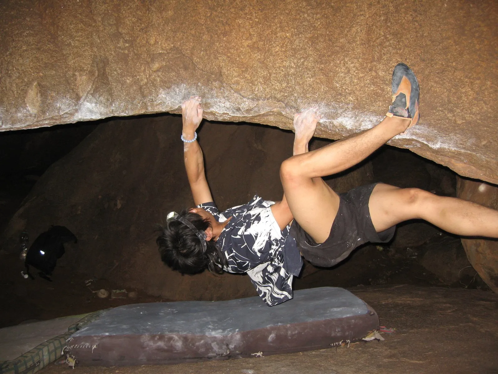 Bouldering upside down under a granite roof, feet above head.
